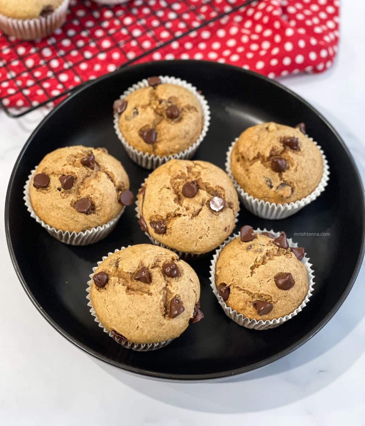 A plate has six almond butter banana muffins.