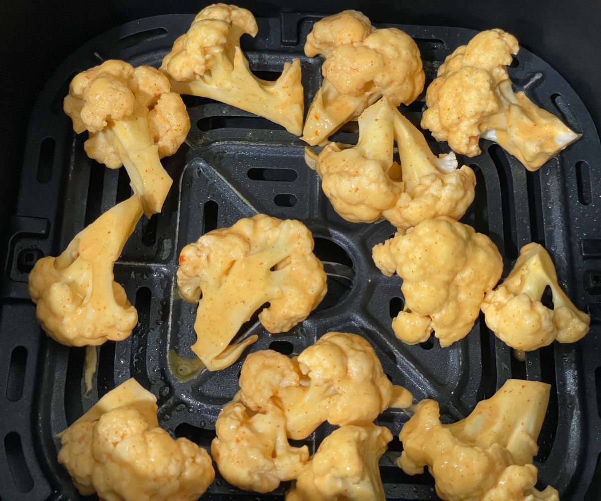 Air fryer basket is with batter coated cauliflower florets.