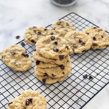 Vegan Chocolate chip cookies are stacked on the cooling wire rack.