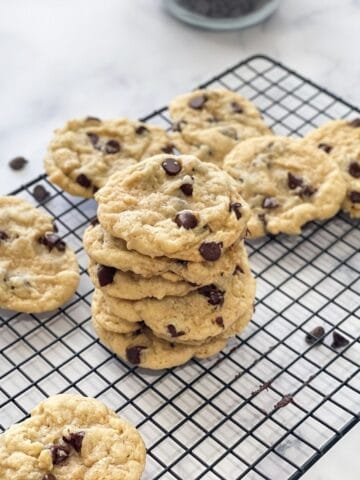 Vegan Chocolate chip cookies are stacked on the cooling wire rack.