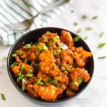 A bowl is filled with air fried Gobi Manchurian snack.