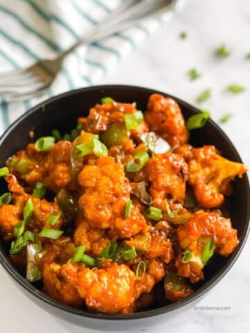 A bowl is filled with air fried Gobi Manchurian snack.