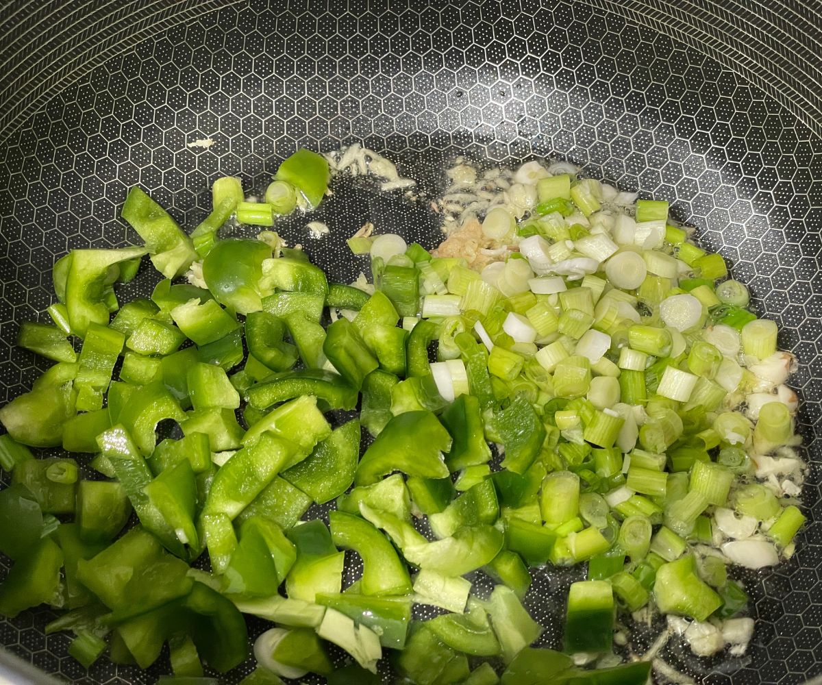 A pan is with green onions, bell peppers for the Gobi Manchurian sauce.