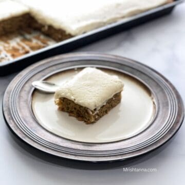 A plate is with sliced vegan banana cake and spoon on the table.
