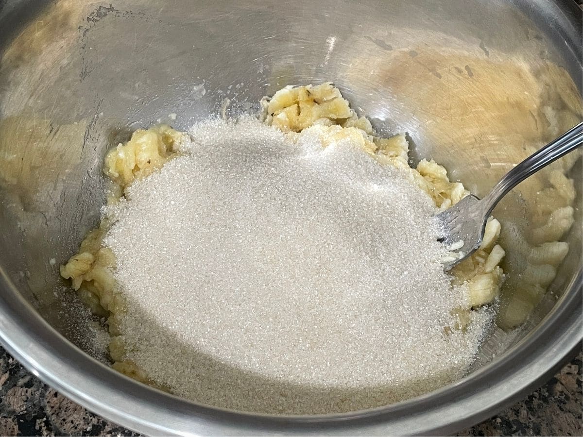 A bowl is with mashed bananas and sugar