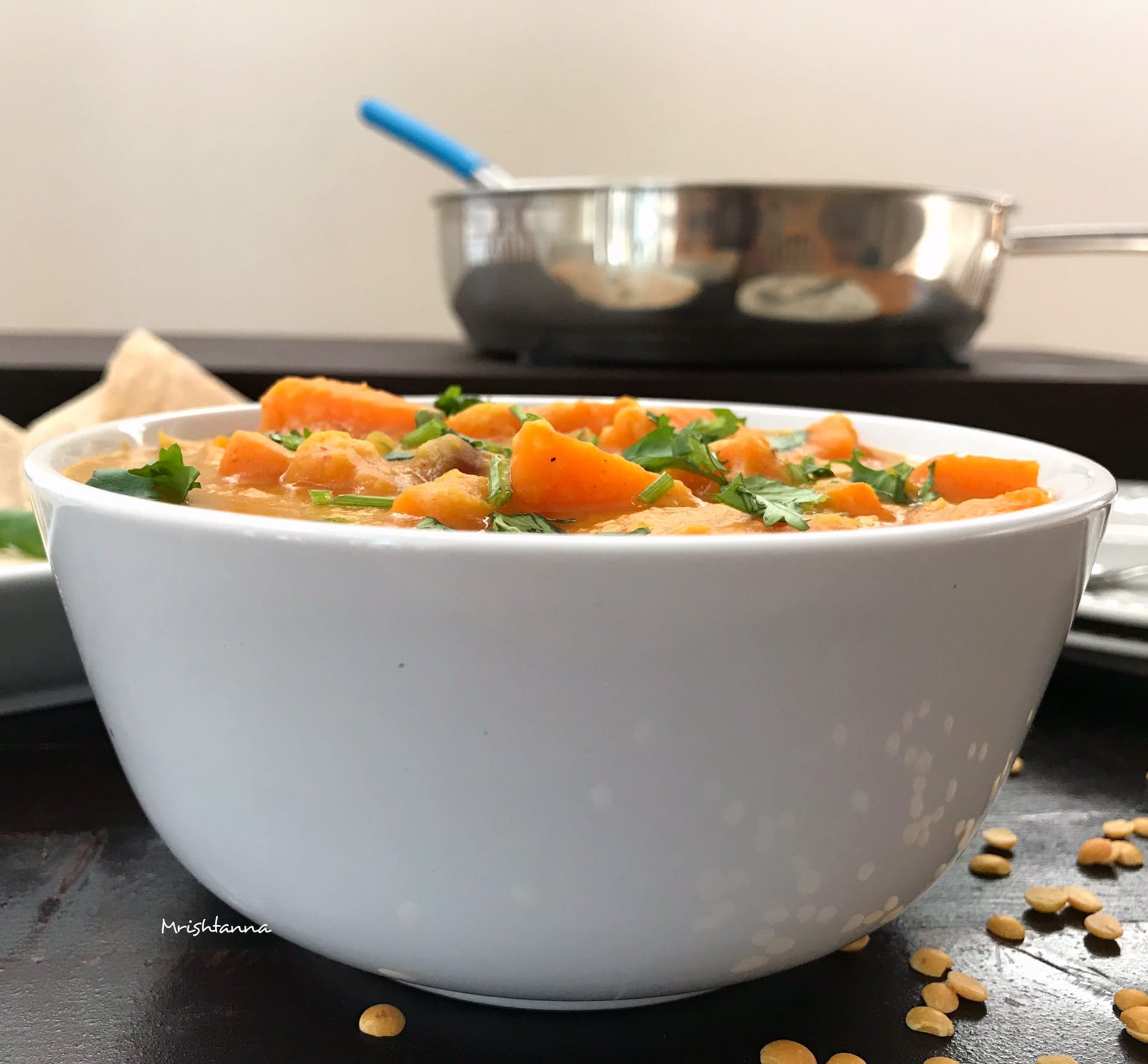 A bowl of food on a table, with Pumpkin and Dal