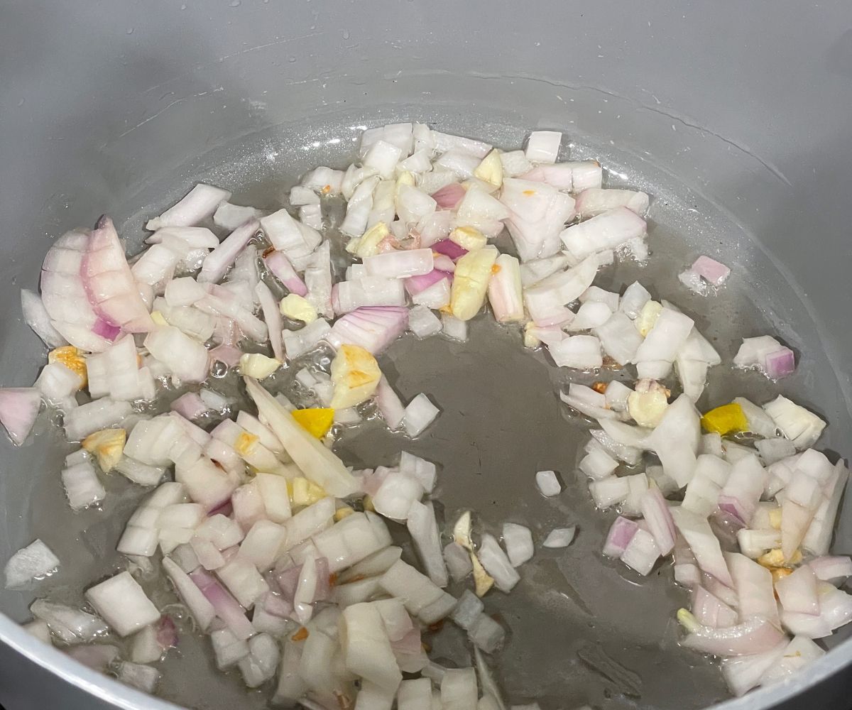 a vessel is with oil, garlic and chopped onions over the heat.
