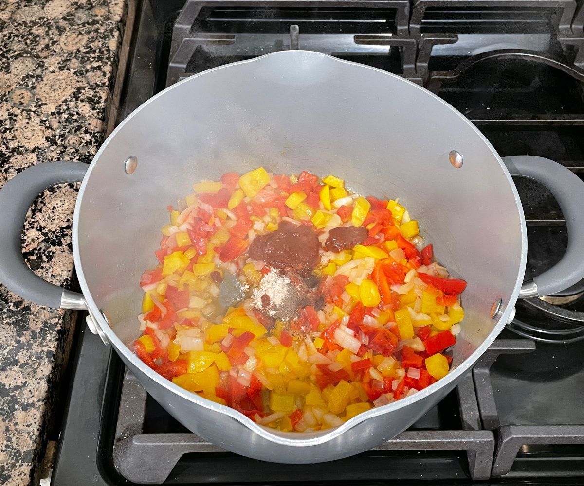 a vessel is with bell peppers and spices over the heat.