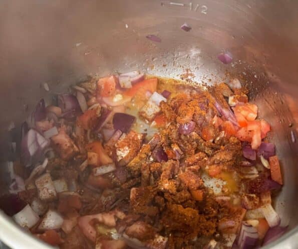 A pot is with spices, tomatoes,and onions.