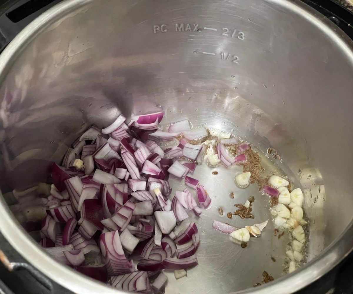 An instant pot is with onions and garlic on saute mode.