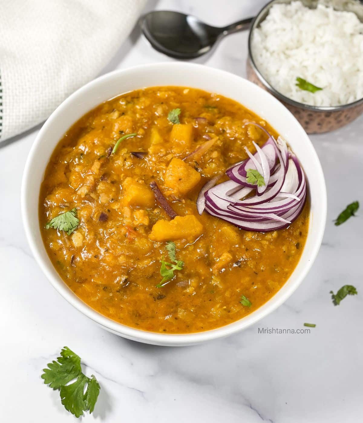 A bowl of Instant pot  pumpkin dal is on the surface.