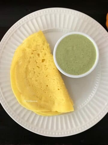 A plate is with pumpkin dosa with chutney