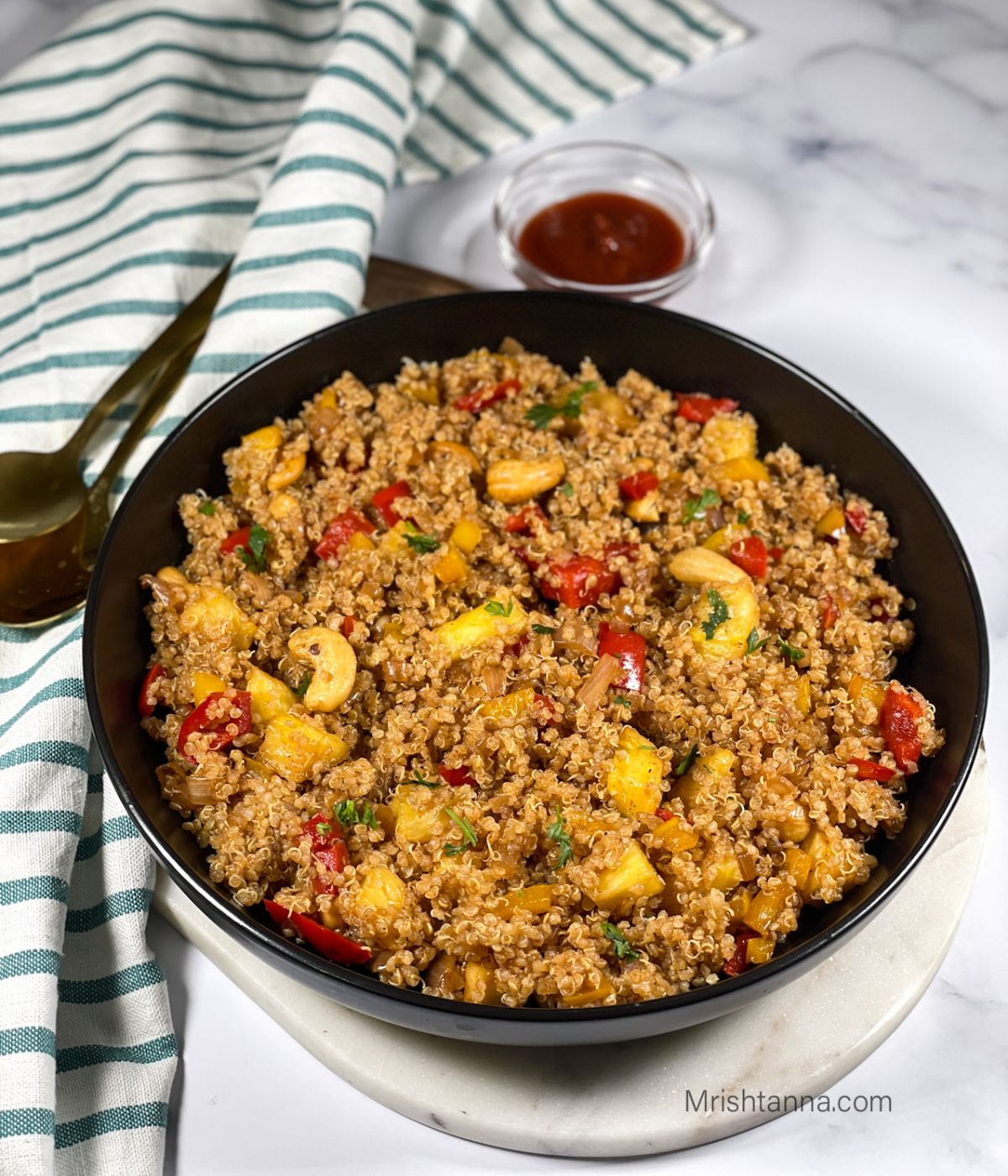 A black plate is with pineapple quinoa.