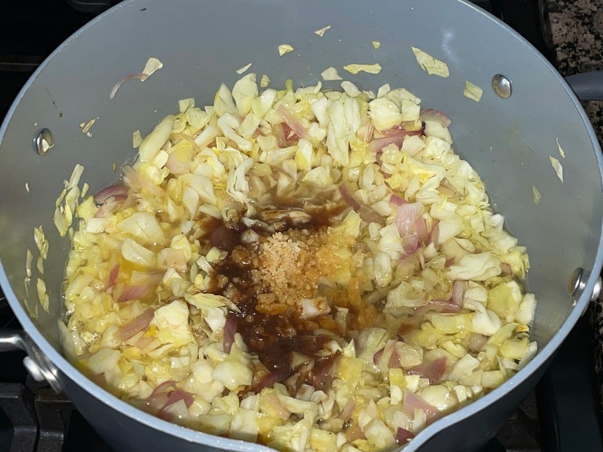 A pan is with cabbage, onion and salt over the heat