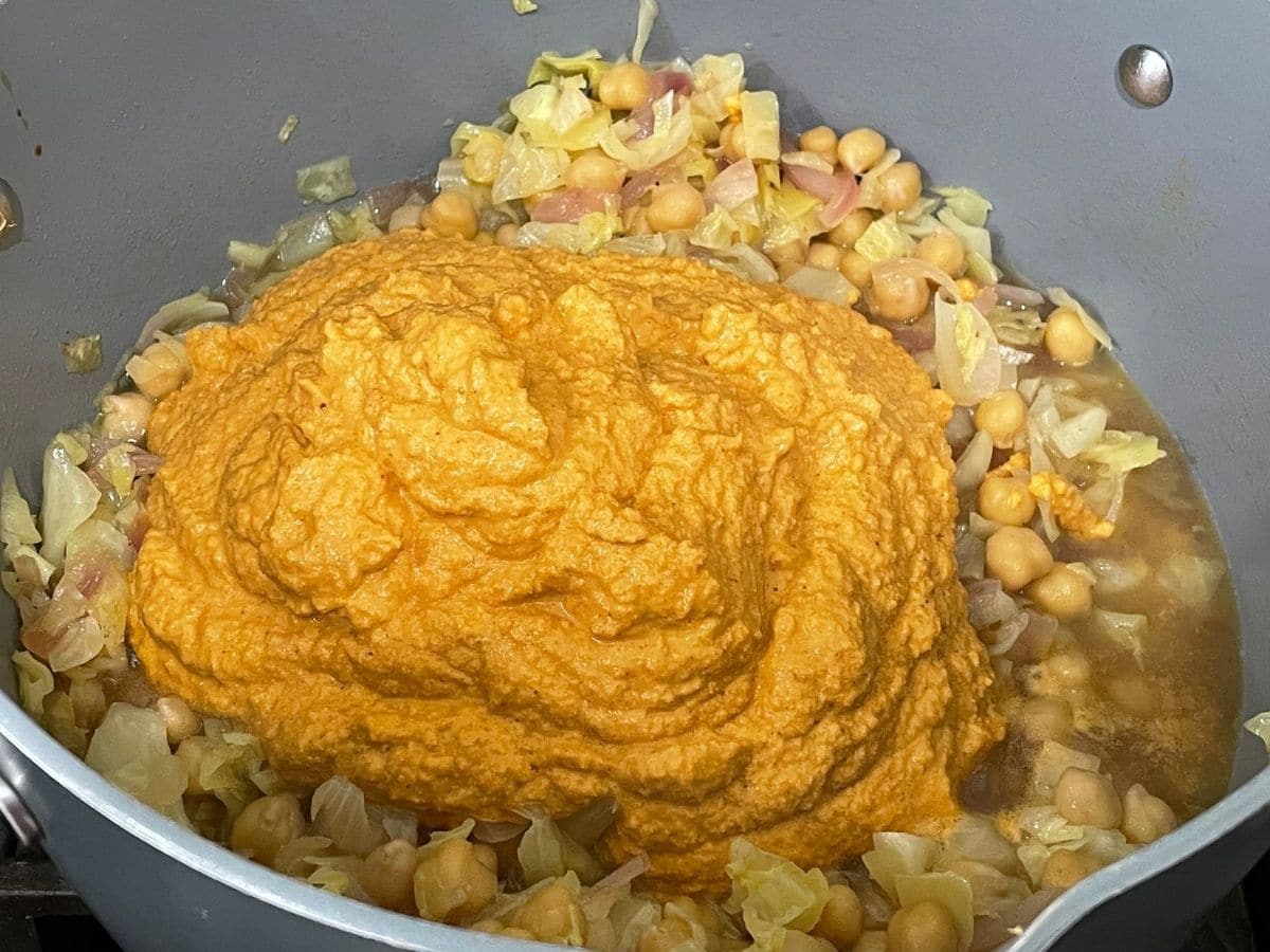 A pan is with blended paste and cooked chickpeas and cabbage