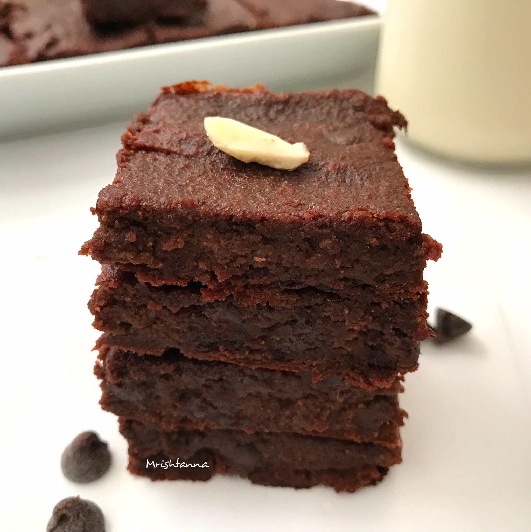 A stack of chocolate brownie on a plate with glass of milk 