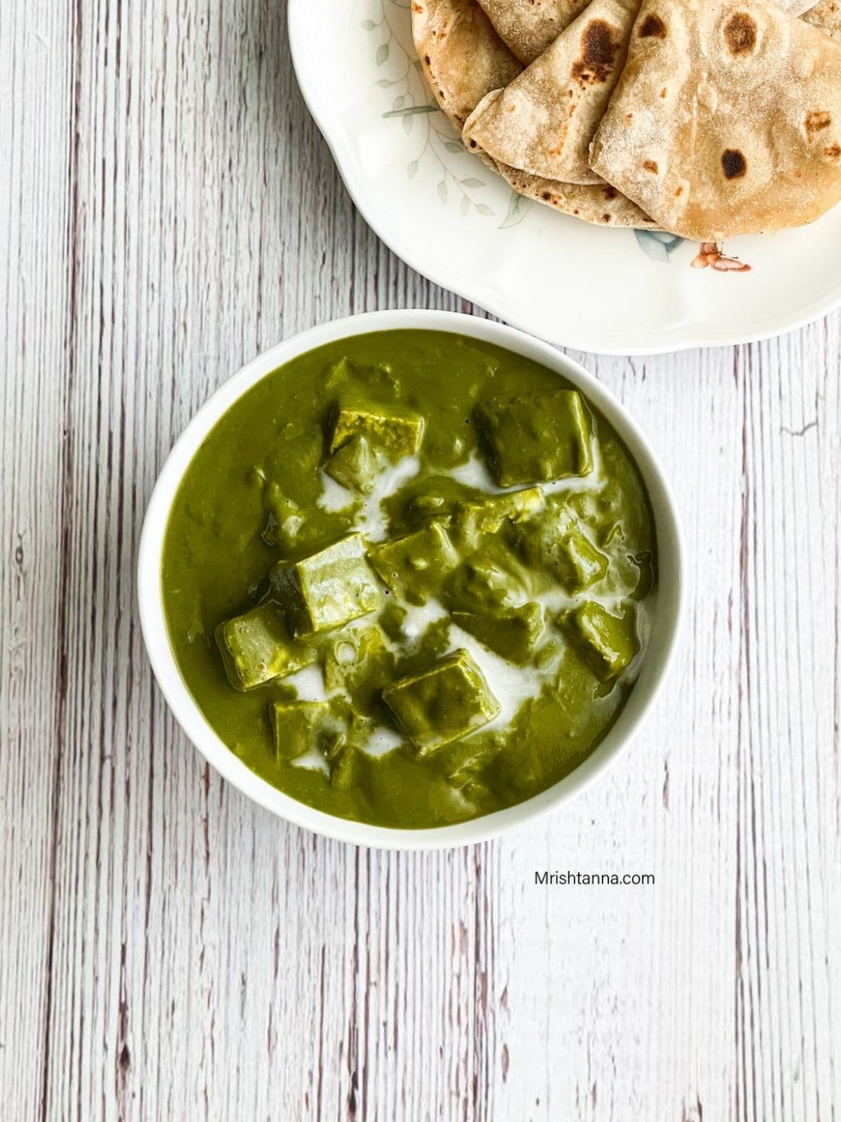 Close up of a bowl with palak tofu and roti is on the side of the table