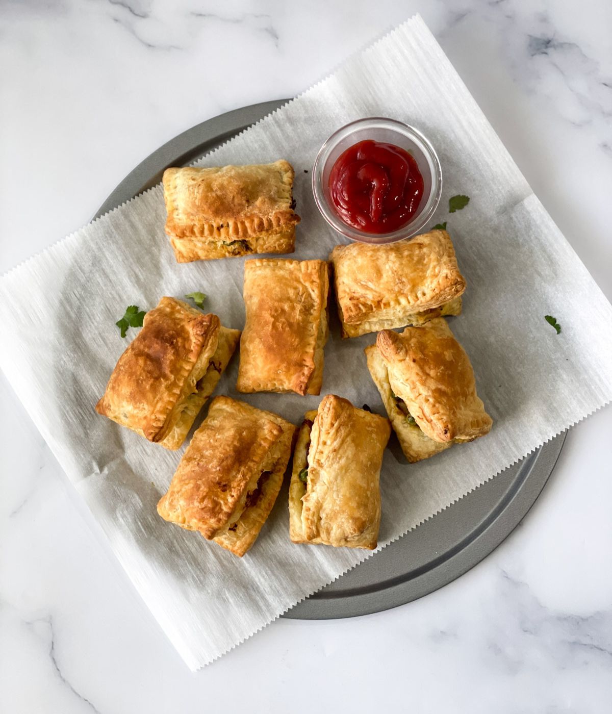 A tray is with veg puff and tomato ketchup.