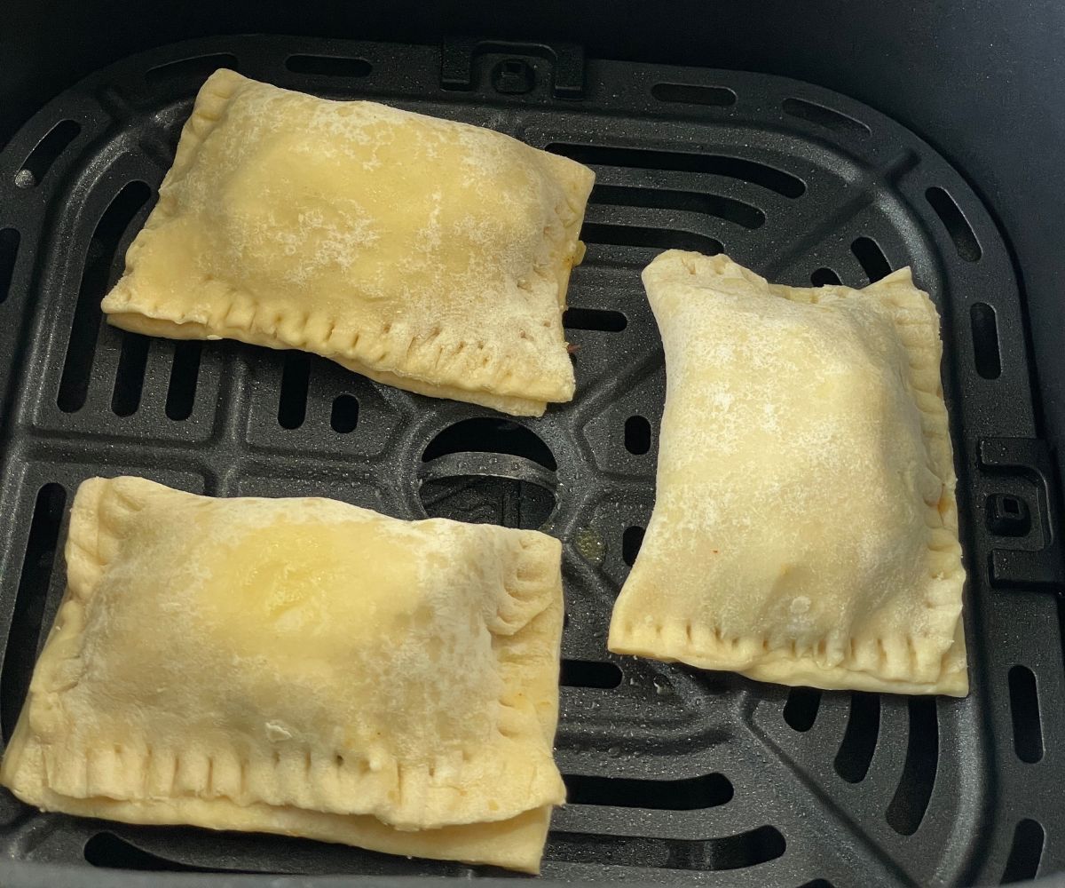 Veg puff are inside the air fryer basket.