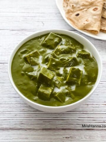 A bowl is with palak tofu gravy on the table.