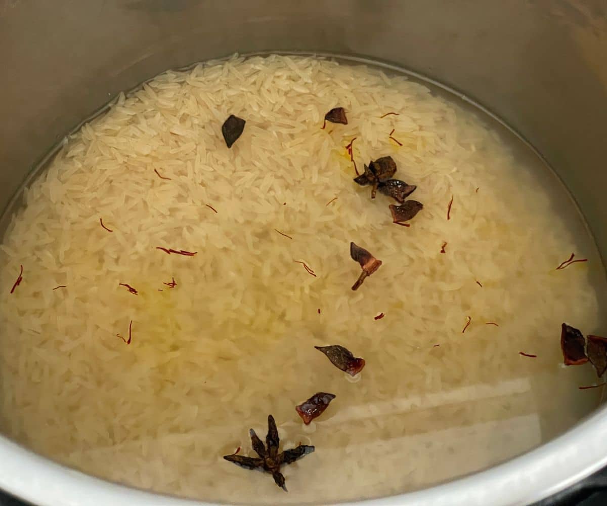 An instant pot is with basmati rice and saffron for biryani.