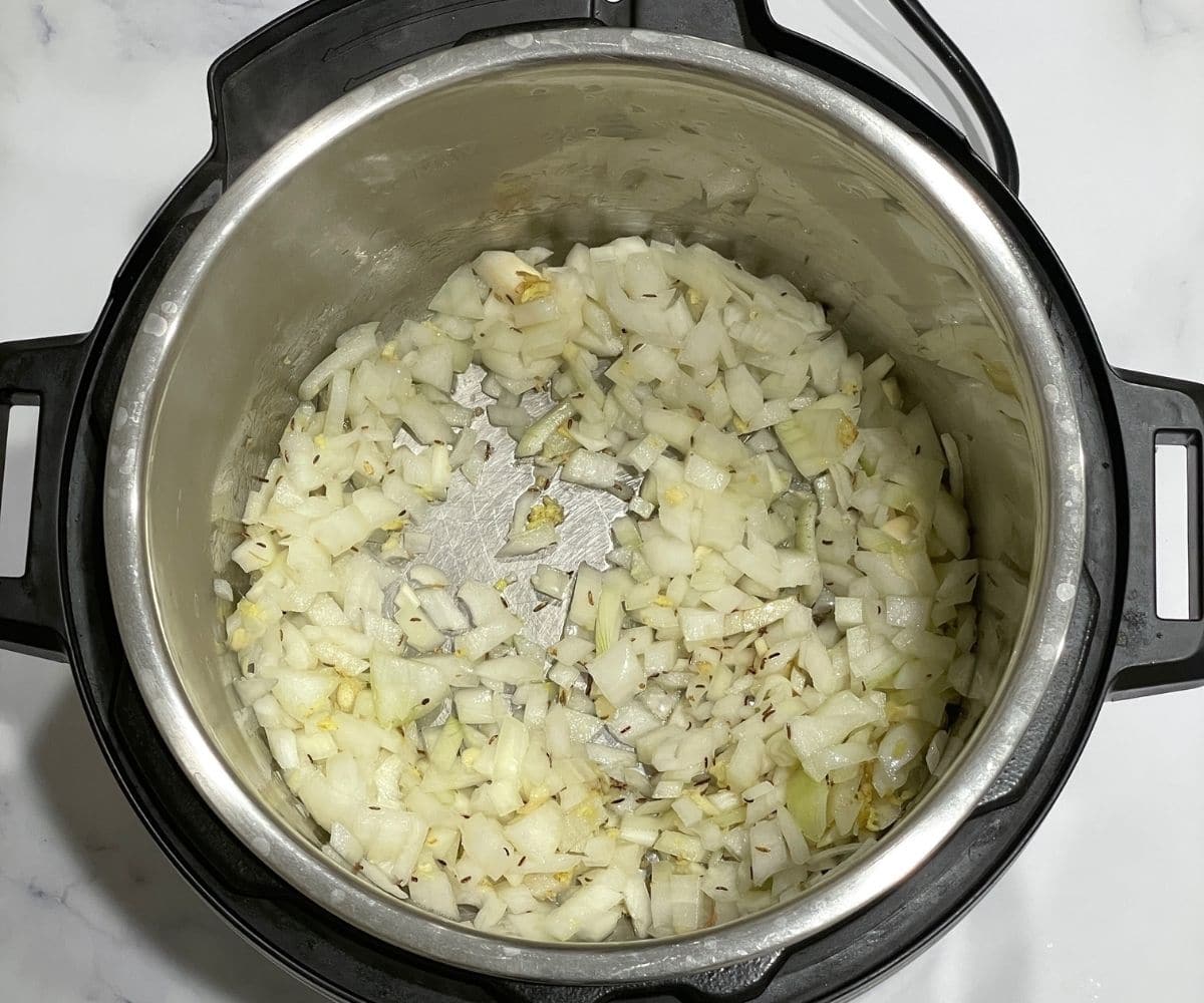 An instant pot is with onions on saute mode.