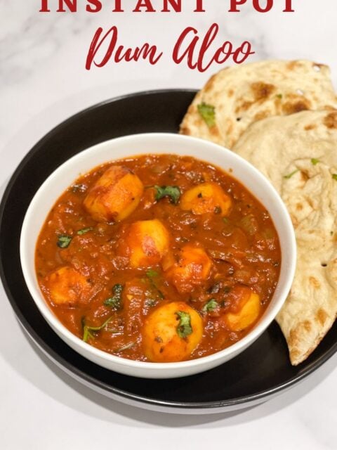 A bowl of dum aloo curry is on the table.