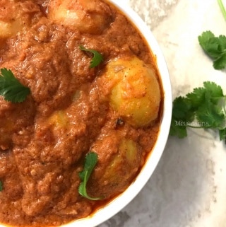 A close up of a plate of food with stew, with Dum Aloo