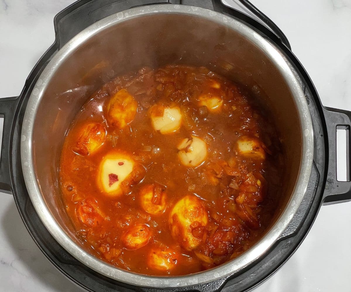 An instant pot is with babay potatoes and masala on cooking mode.