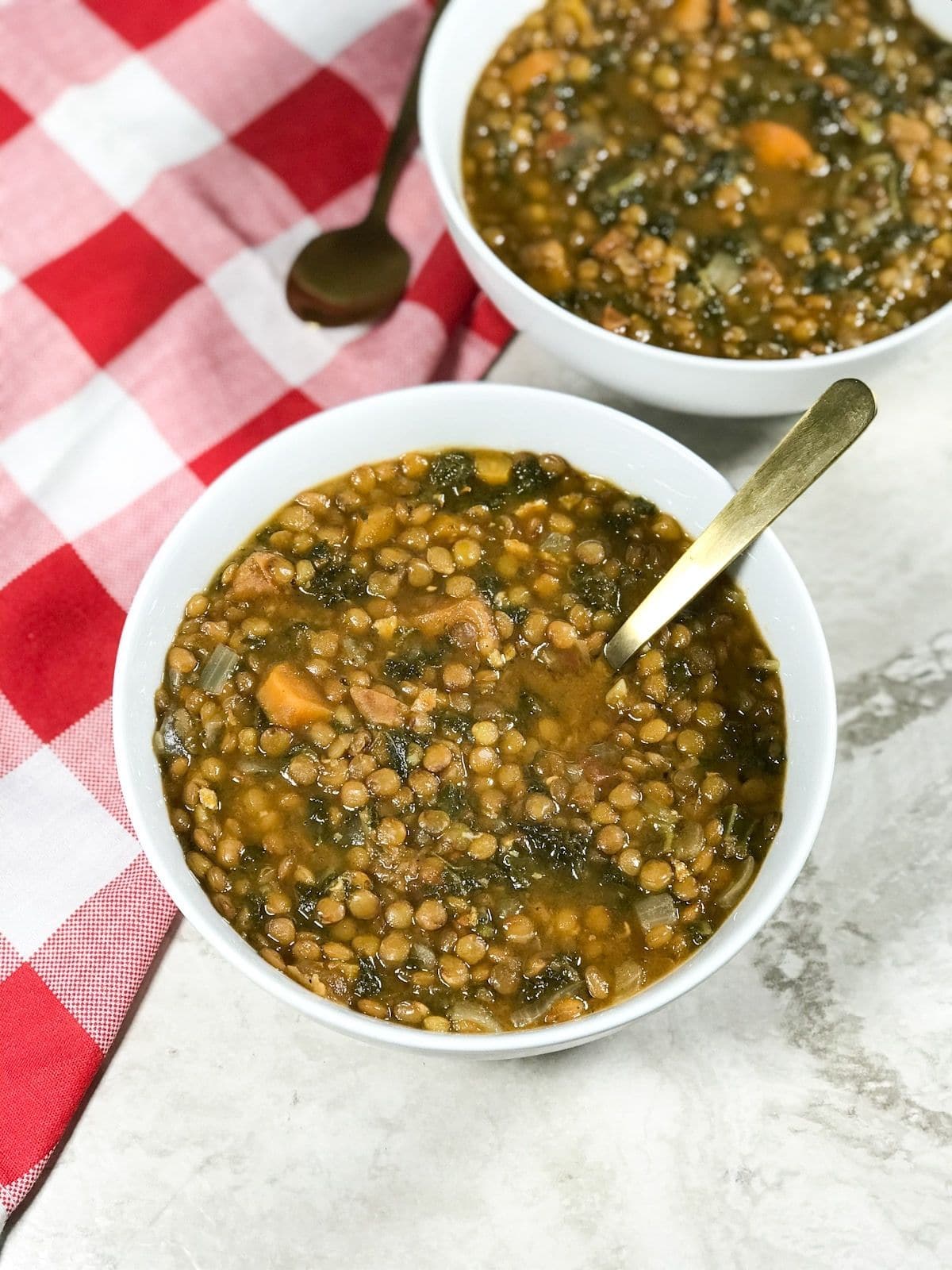 A white bowl is with kale and lentil soup and placed on the table