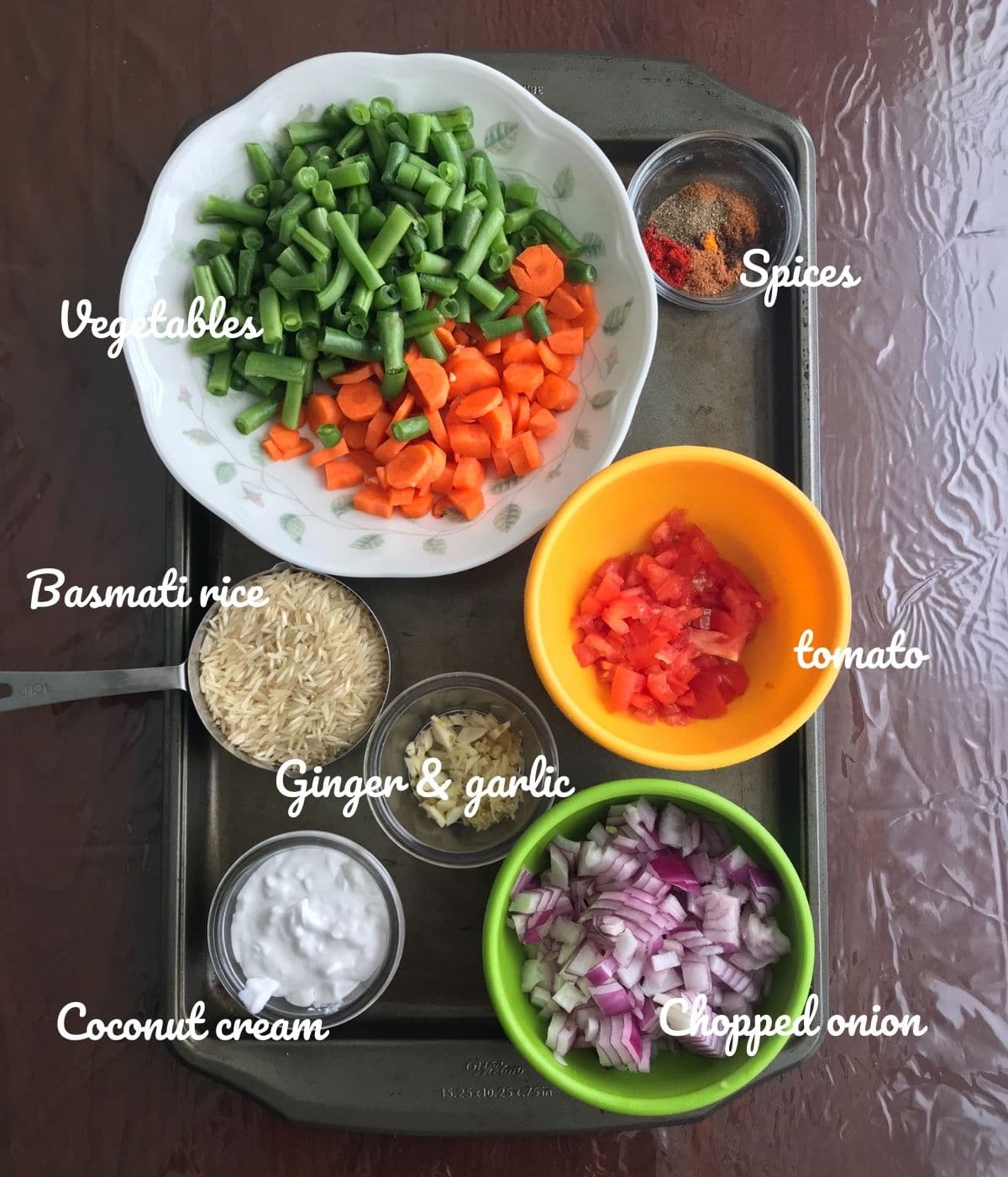 A table is filled with vegetable rice ingredients like rice, vegetables, and spices