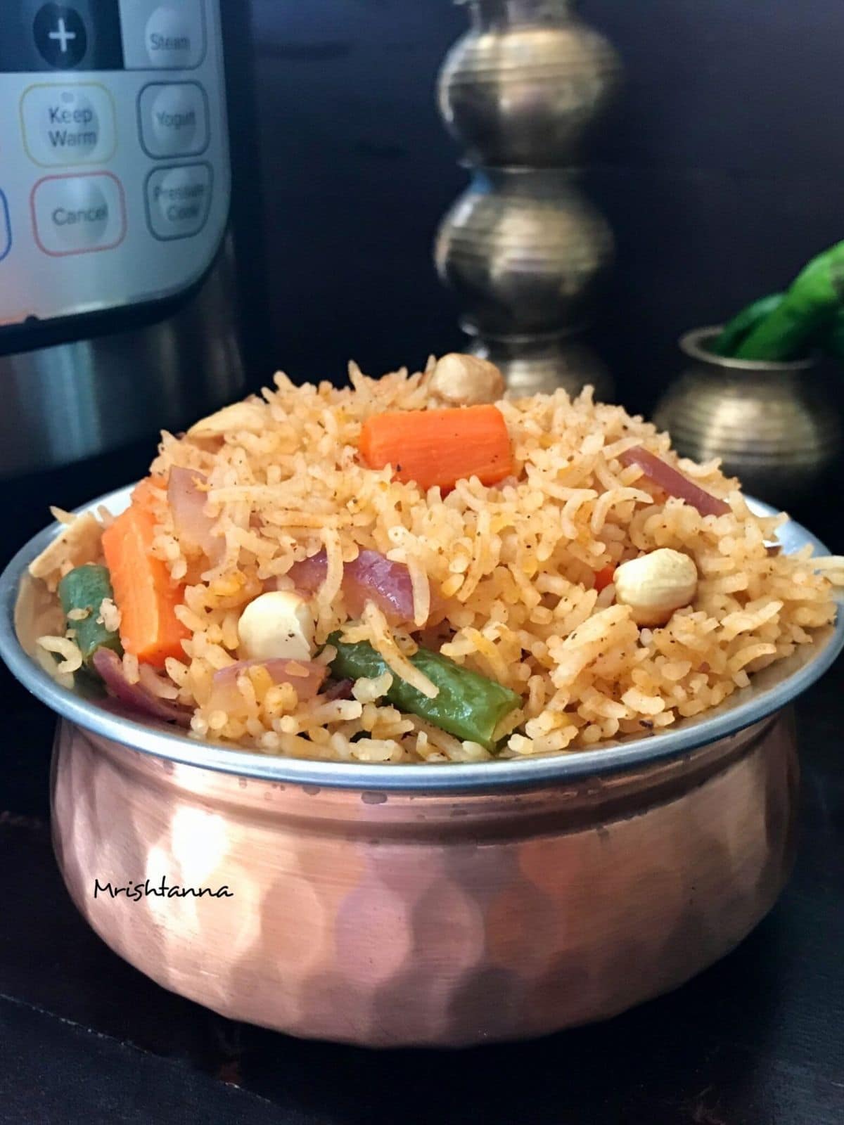 A pot is filled with vegetable pulao and placed on the black table