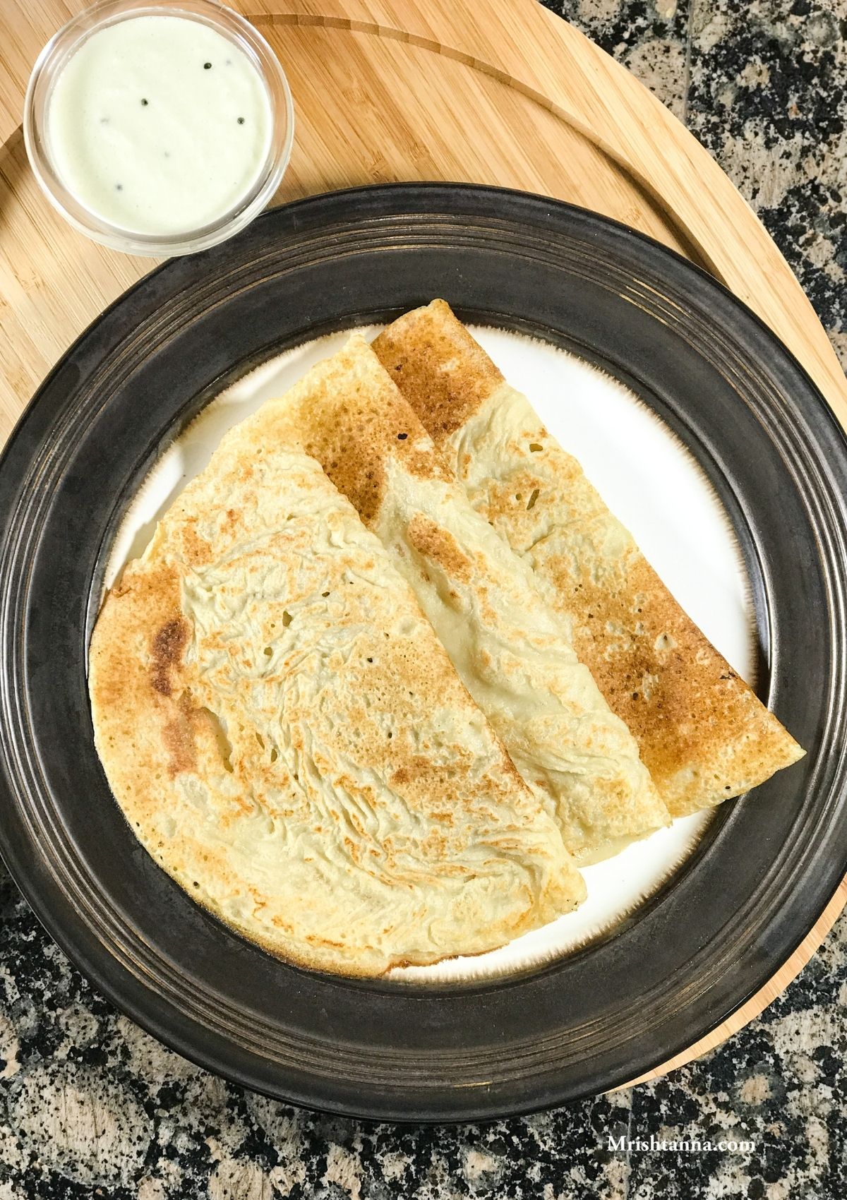 A plate of oats dosa and bowl of chutney is on the table