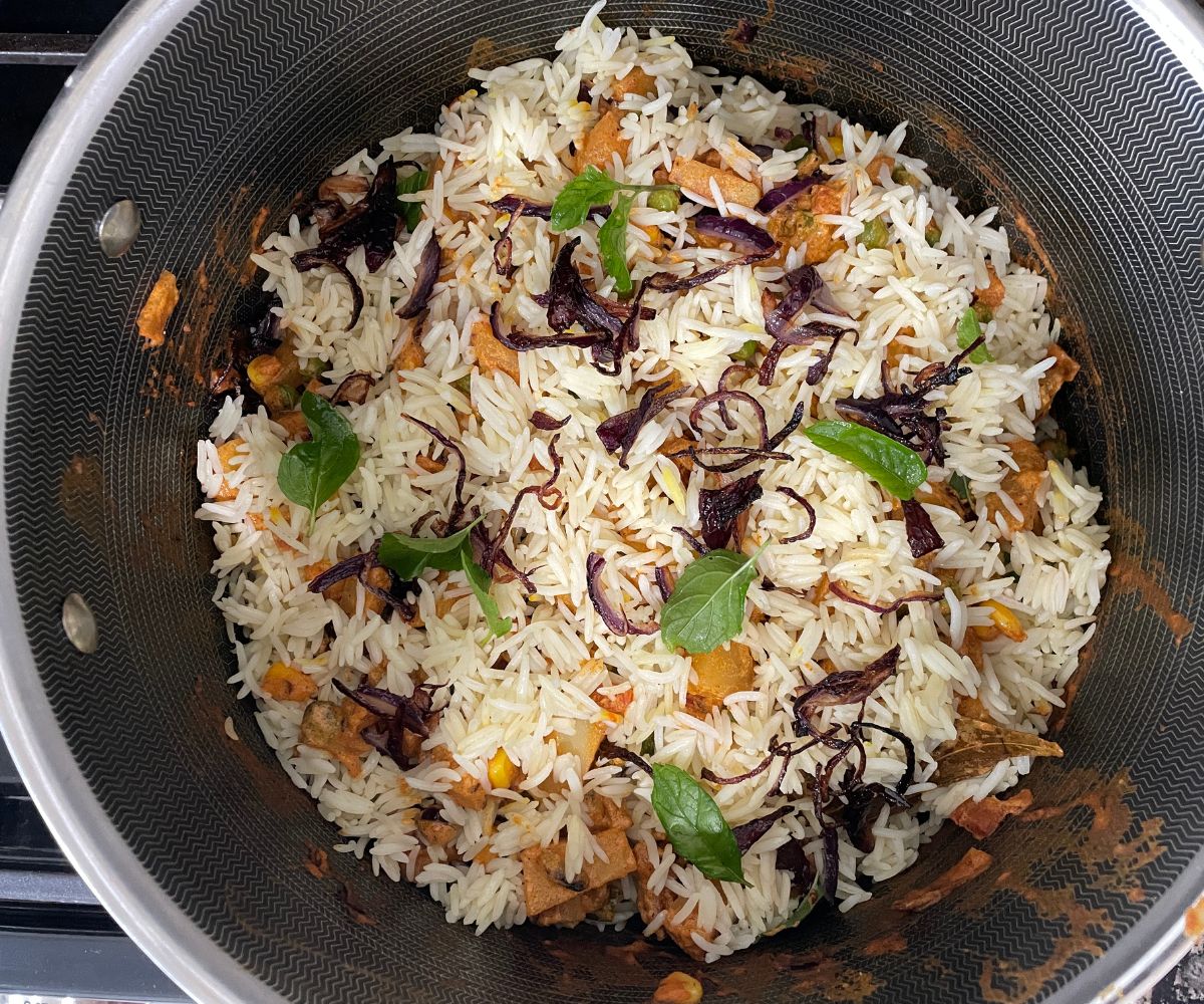 A pot is with layered vegan biryani.