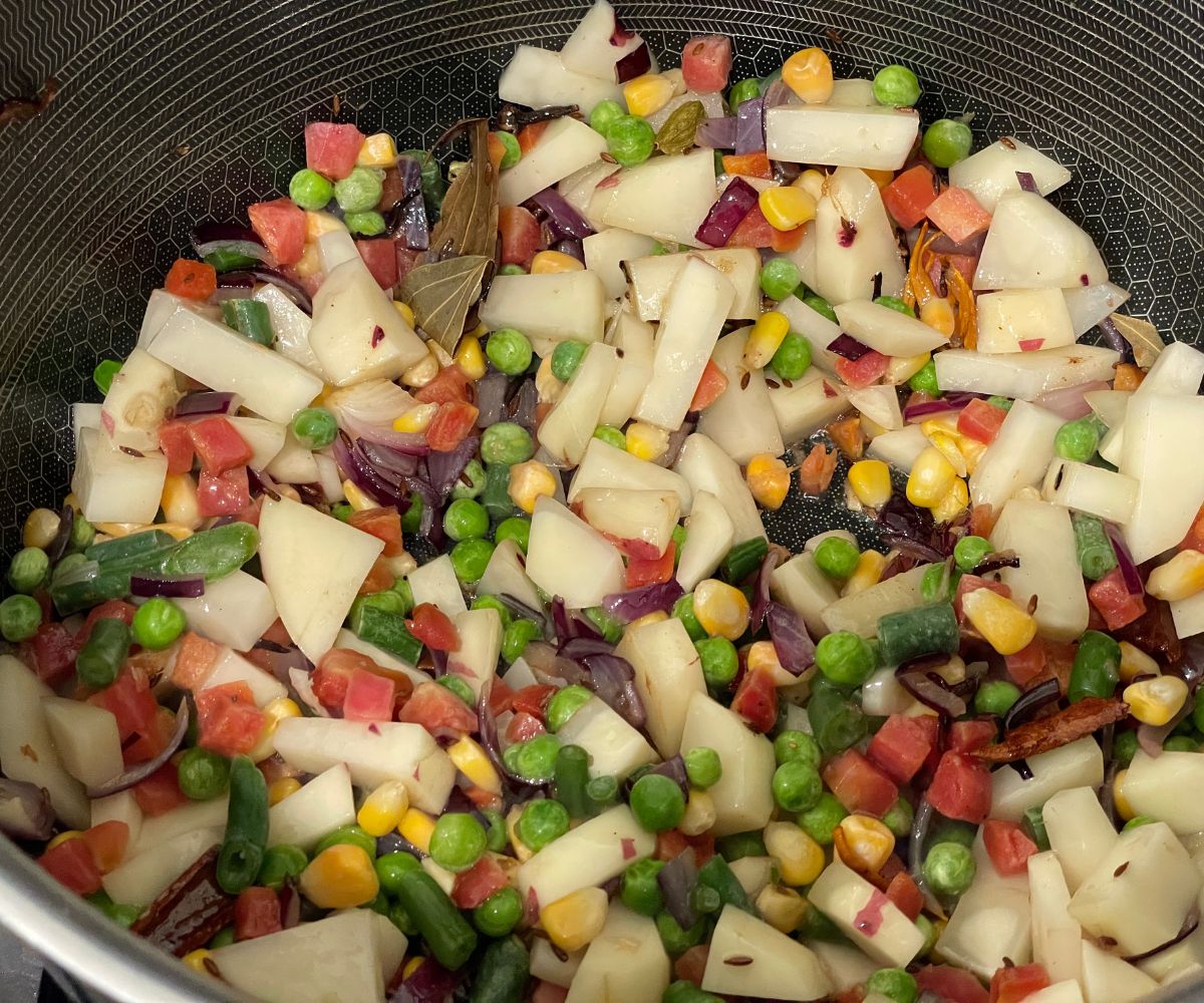 A pot is with biryani masalas and vegetables.