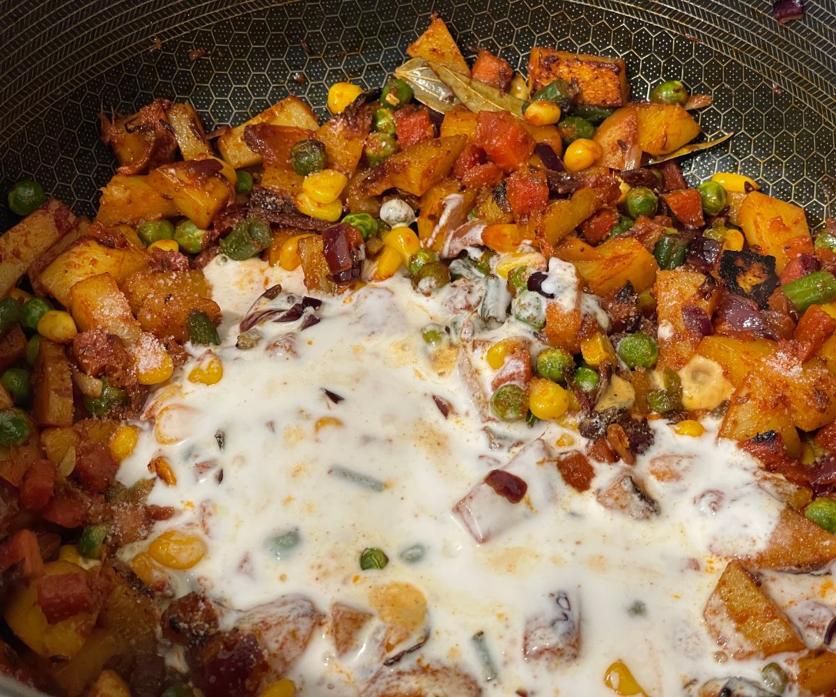 A pot is with spices, vegetables and vegan yogurt for biryani masala.