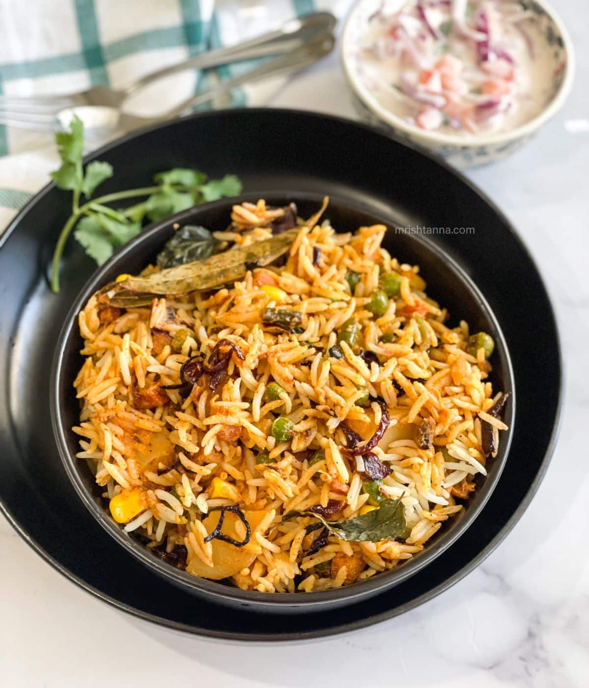 A bowl is filled with vegan dum biryani on the plate.