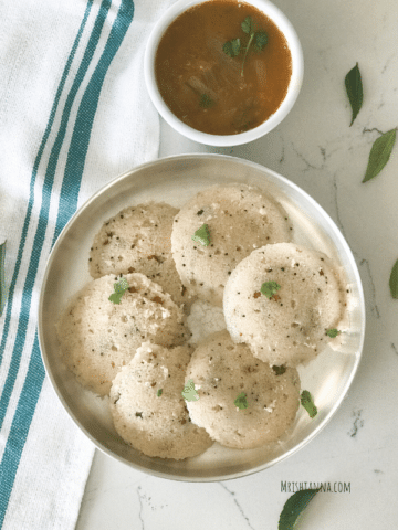 A bowl of food on a plate, with Rava idli