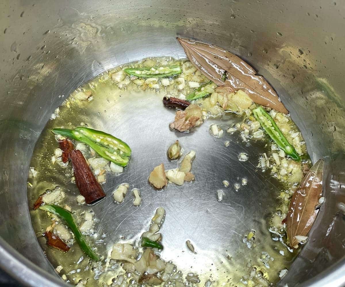 An instant pot is with garlic, ginger and green chilies for peas pulao.