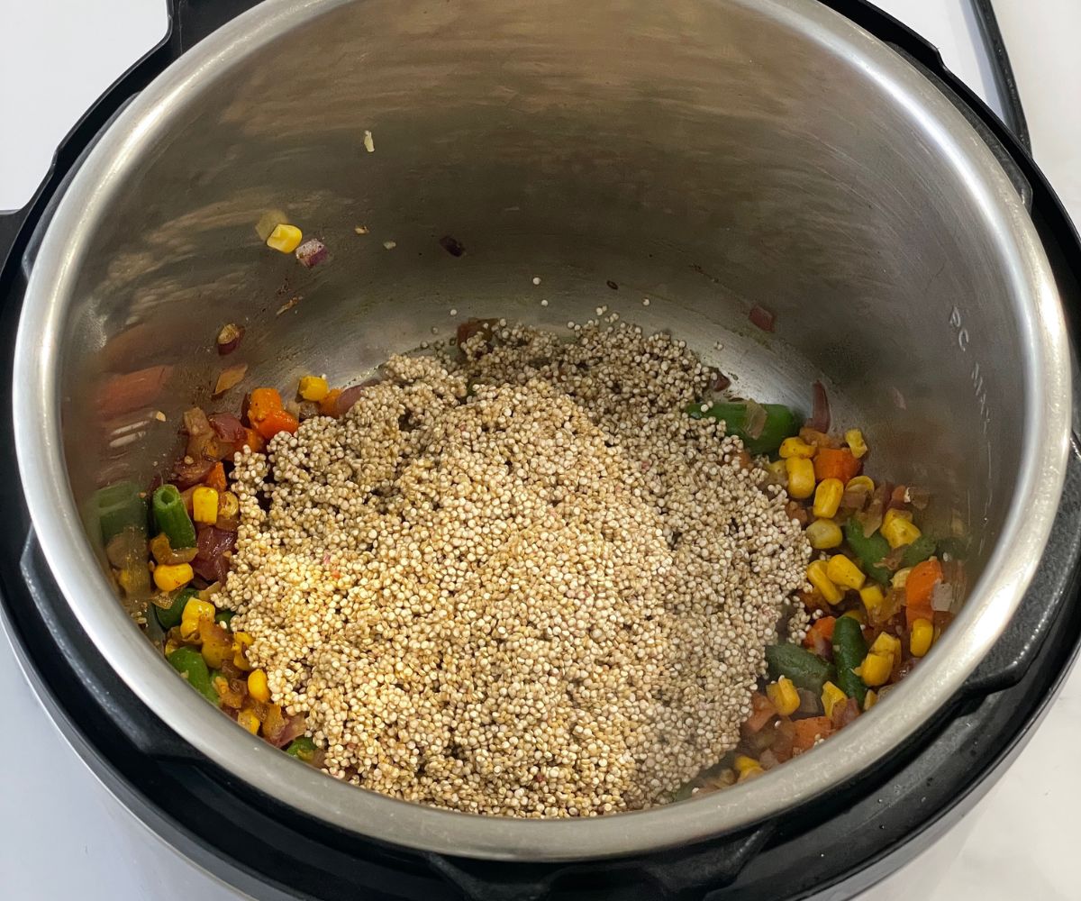 An instant pot is filled with quinoa, vegetables and spices for pulao.