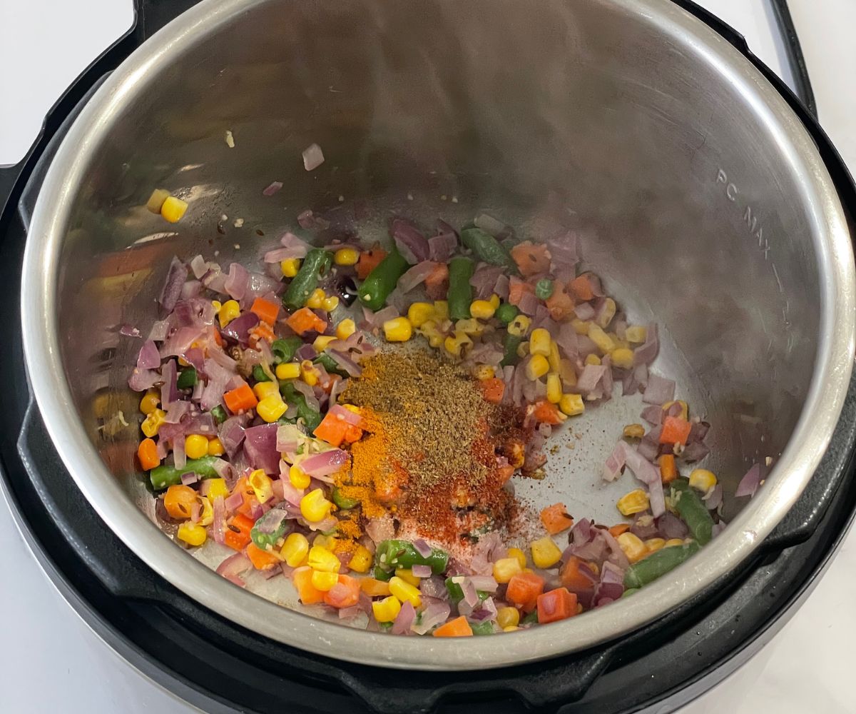 heated instant pot is with mixed vegetables and spices for quinoa pulao.