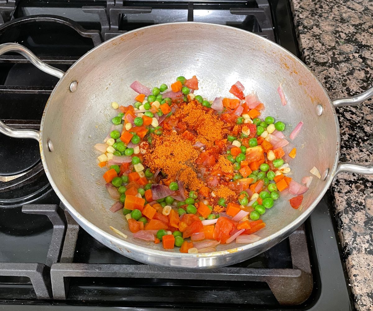 A pot is with veggies, spices on the stove top.