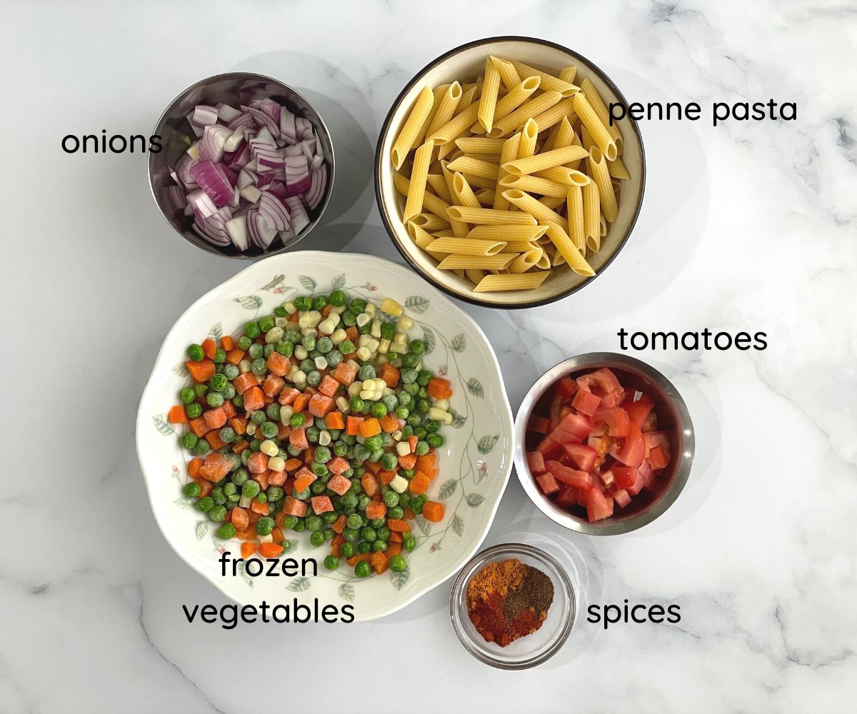 Masala pasta recipe ingredients are on the white surface.