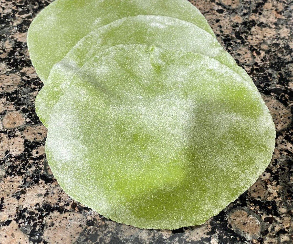 Rolled flat palak paratha dough is on the counter top.