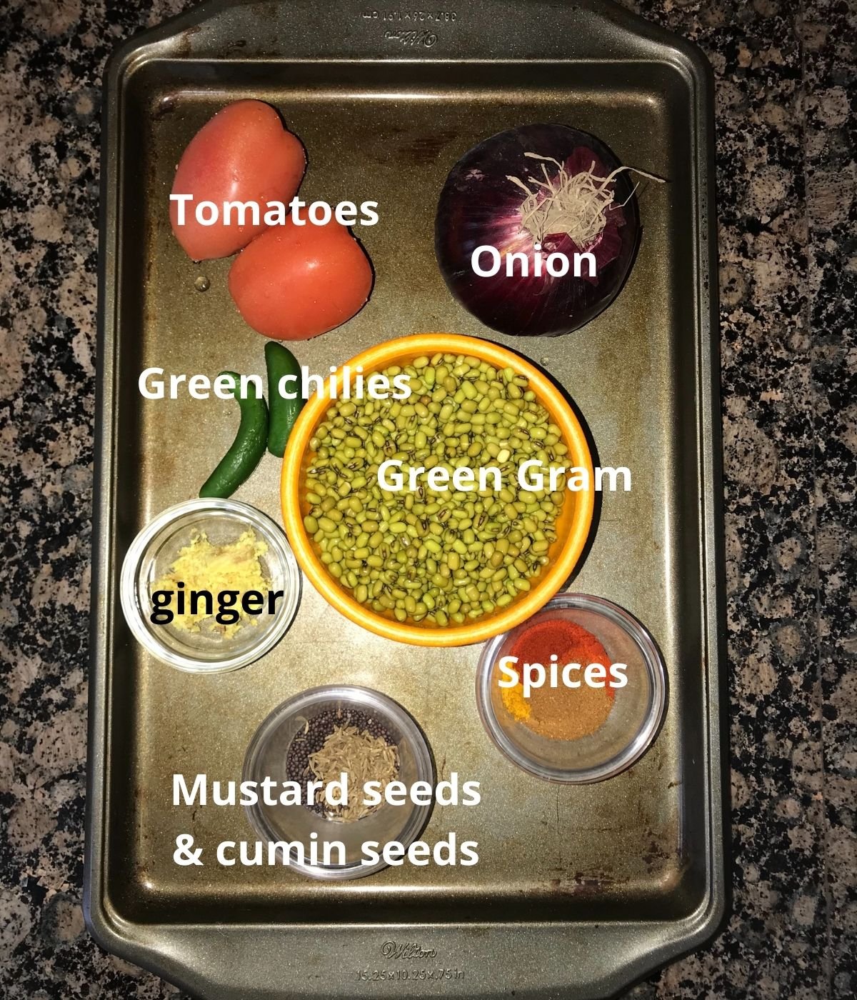 A tray is filled with dal ingredients like onion, tomatoes, green gram,spices