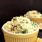 A bowl of lemon rice is on the table with side of sliced lemons