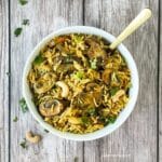 A white bowl is with mushroom rice and topped with cilantro and cashews