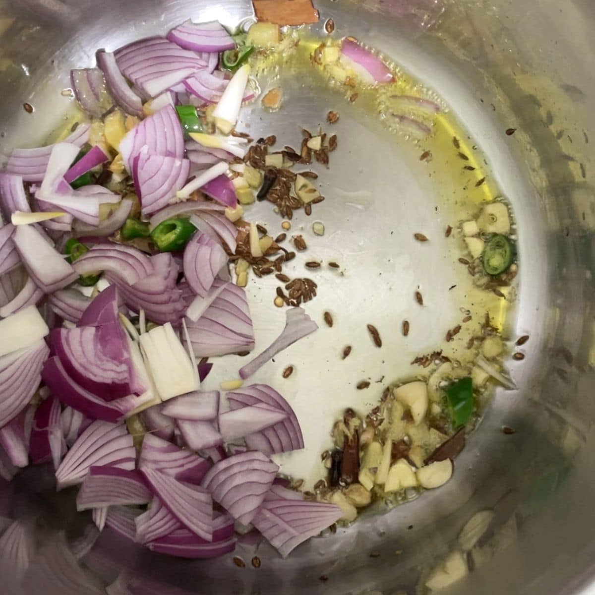 An instant pot is with spices, and onions on saute mode