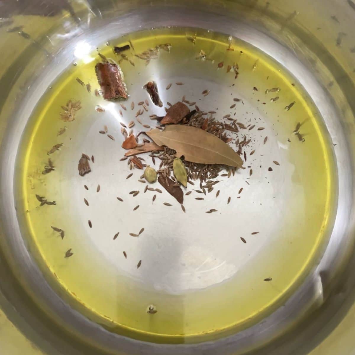 A pot with oil and dry spices for mushroom rice