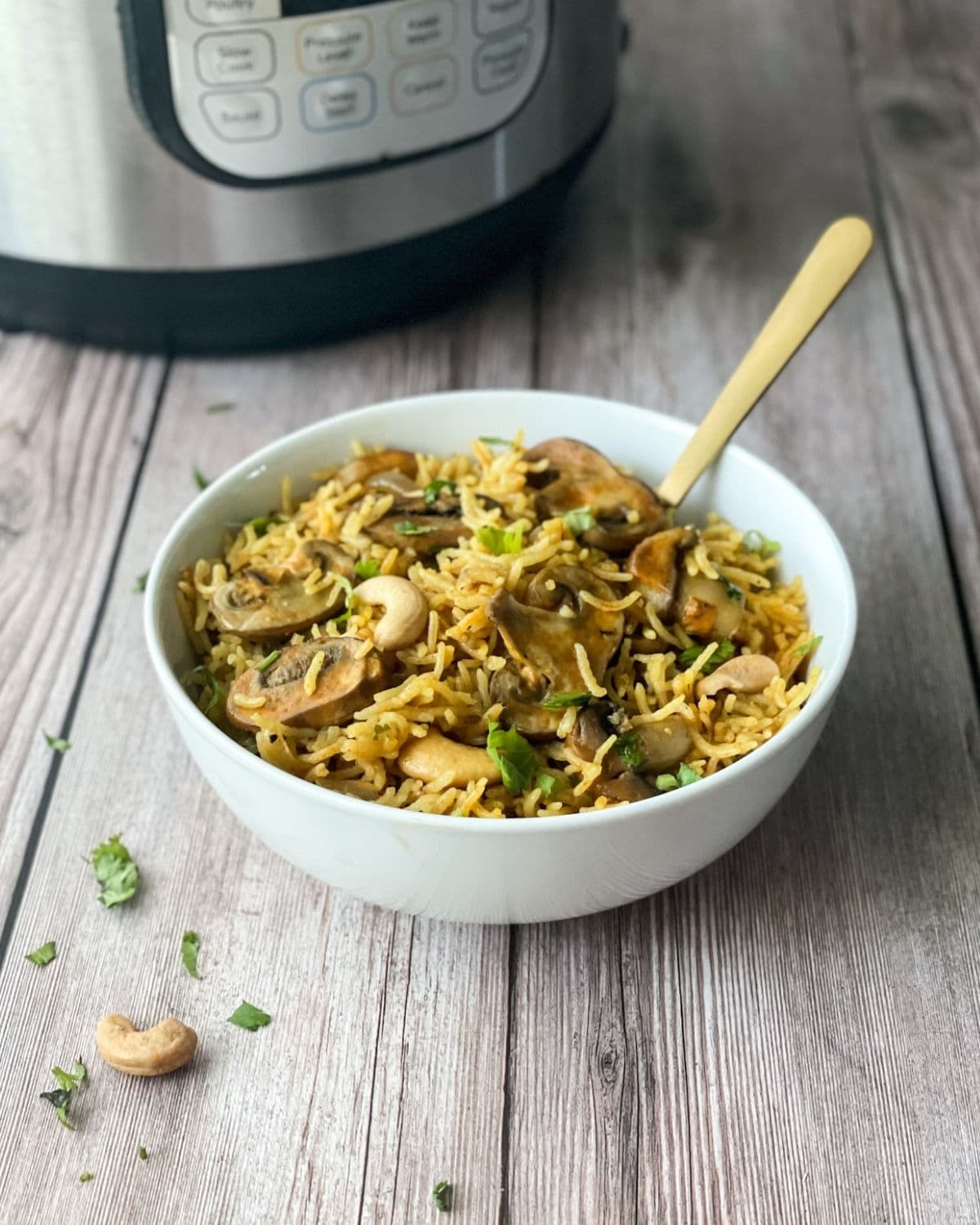 A white bowl is filled with mushroom rice and a golden spoon is inserted.